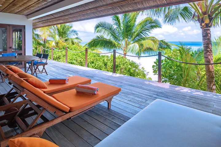 V Villas Maldives at Mirihi — просторная деревянная терраса пляжного люкса с зоной отдыха у океана
