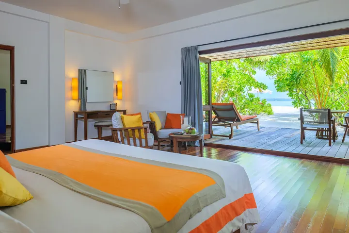 V Villas Maldives at Mirihi — элегантная спальня пляжного люкса с панорамными окнами и выходом на балкон