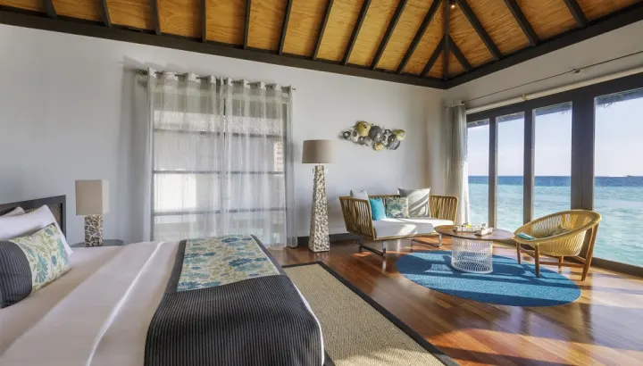 Velassaru Maldives — спальня водной виллы с панорамным остеклением и видом на океан