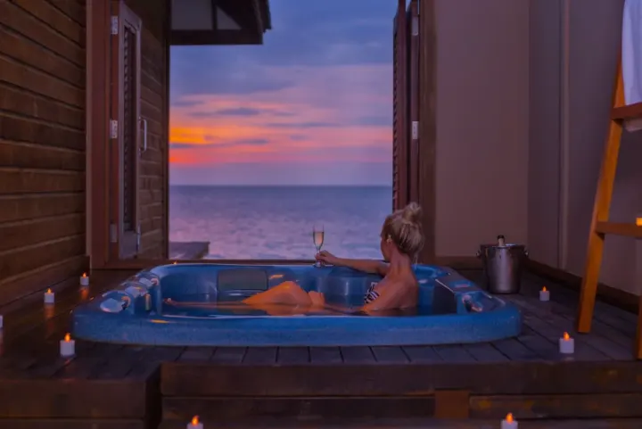Veligandu Island Resort & Spa — гостья отдыхает в джакузи на террасе на закате