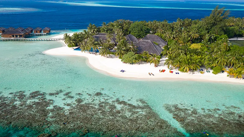 Vilamendhoo Island Resort & Spa — вид сверху на зеленый остров с пляжами и водными виллами