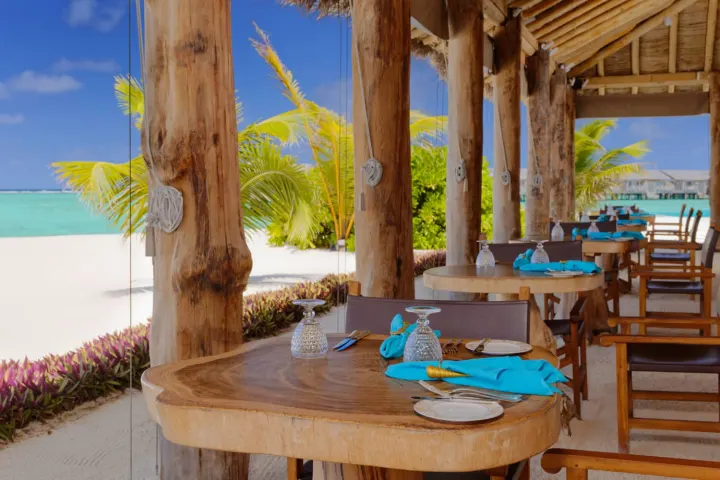 You & Me by Cocoon Maldives — столики ресторана на песчаном полу под открытым небом